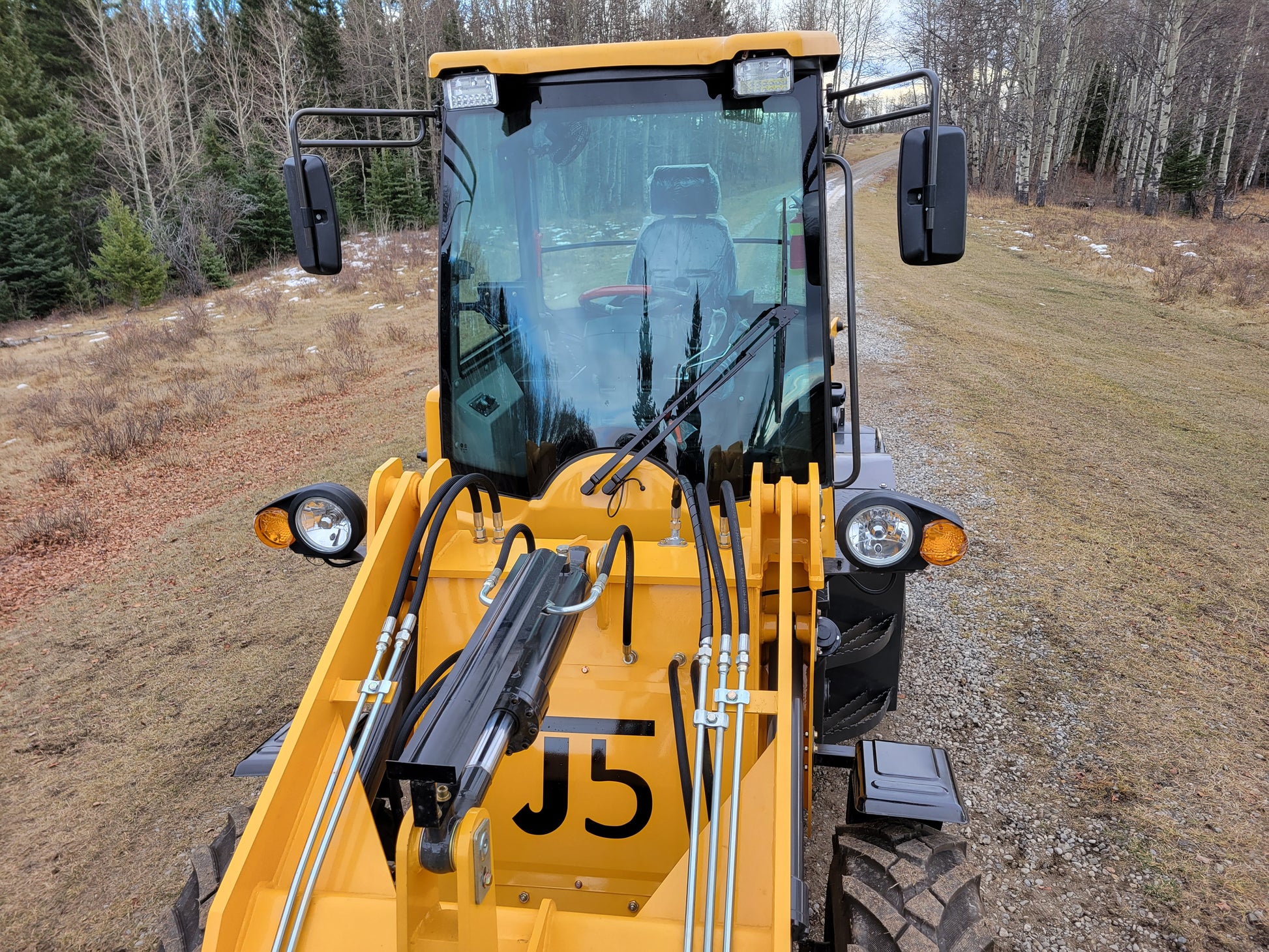 Front view of JT5WL1200 wheel loader showing cabin, headlights, and hydraulic system.