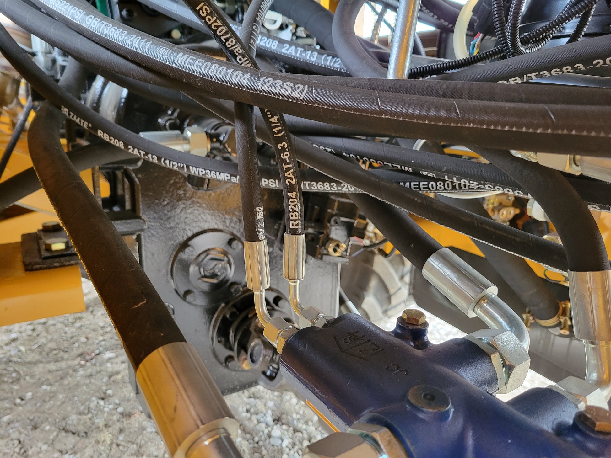 Close-up view of JT5WL1200 wheel loader hydraulic hoses and metal fittings connected to the engine system.