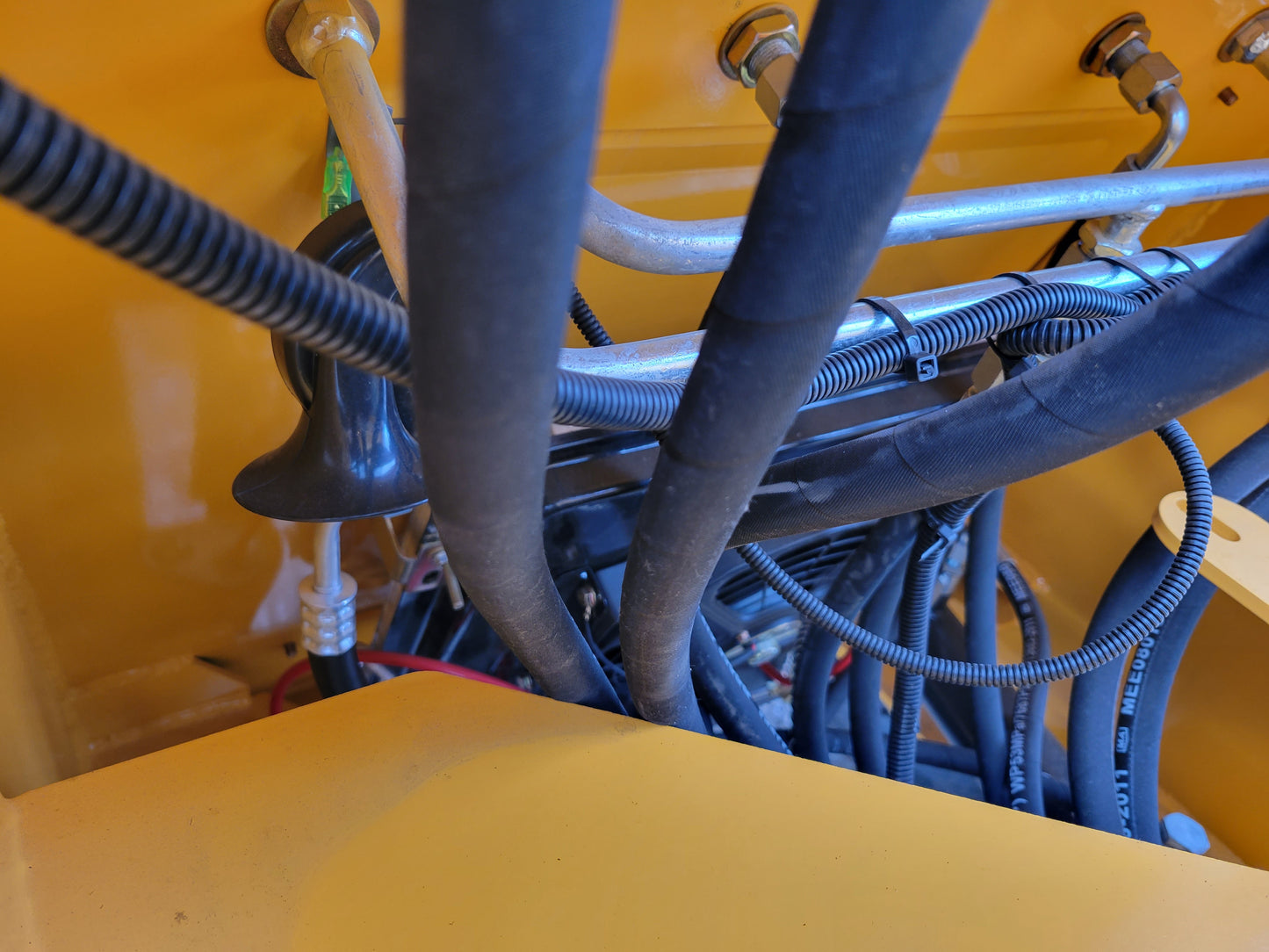 Close-up view of JT5WL1200 wheel loader hydraulic hoses and wiring system.