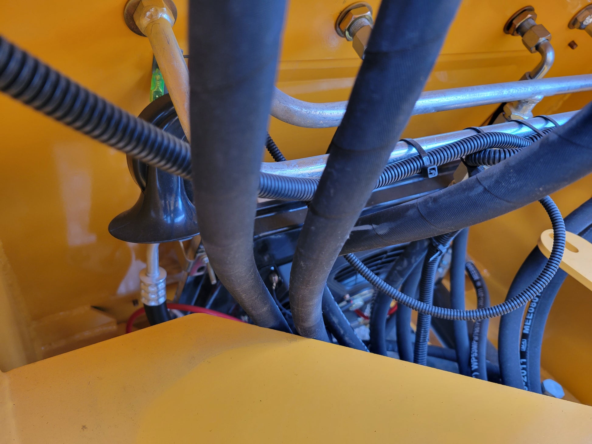 Close-up view of JT5WL1200 wheel loader hydraulic hoses and wiring system.