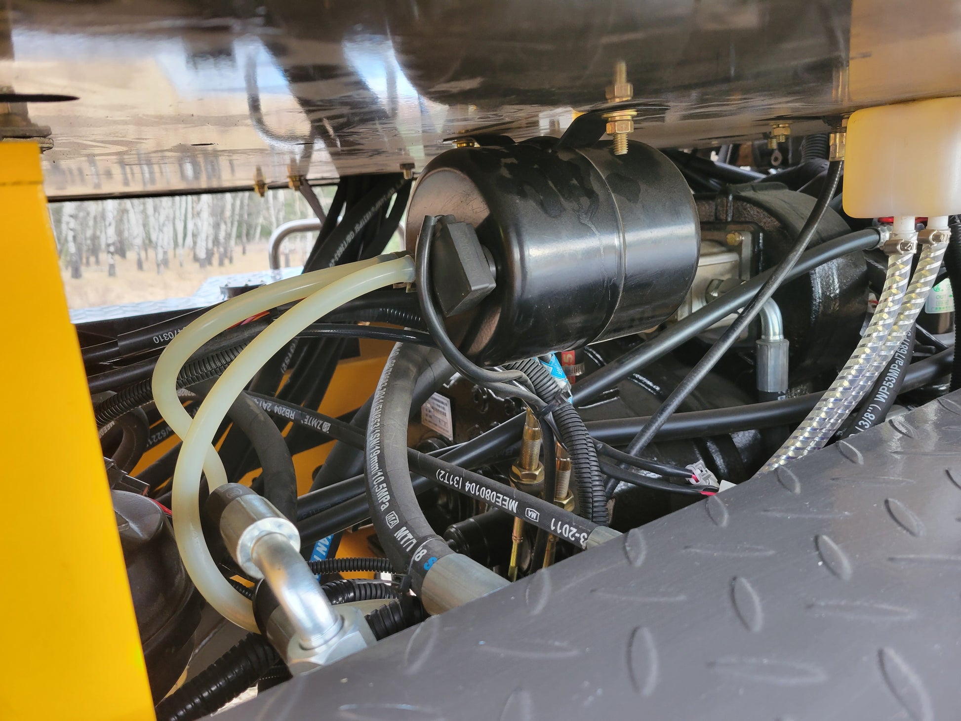 Close-up view of JT5WL1200 wheel loader hydraulic hoses, filter, and fluid system components.