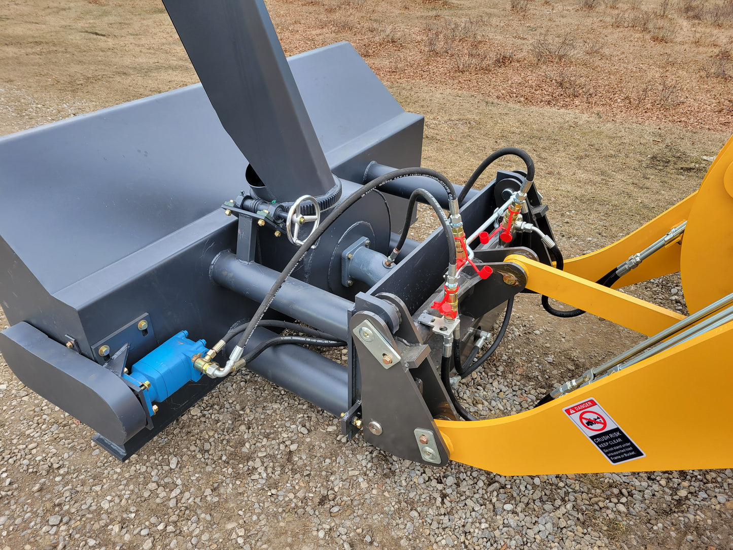 Close-up view of JT5WL1200 wheel loader hydraulic connections with snow blower attachment, heavy-duty hydraulic system for efficient snow removal.