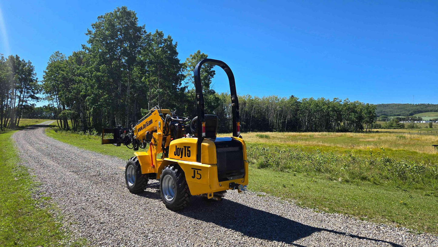 JT5WL800 compact wheel loader on farm road with forklift attachment for landscaping and light construction work in Canada

