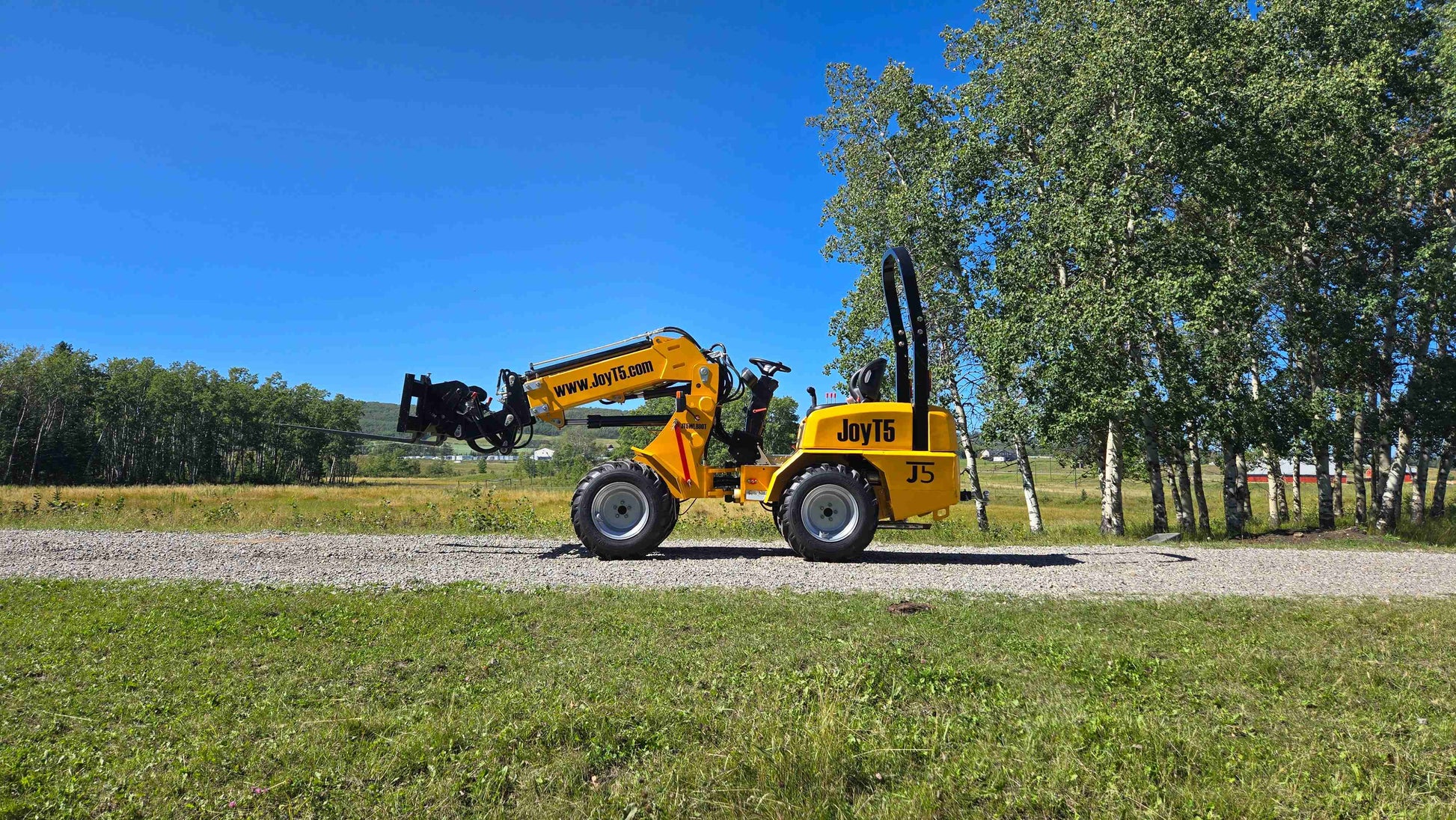 JT5WL800 compact wheel loader extending forklift attachment forward for versatile farm landscaping and construction work in Canada