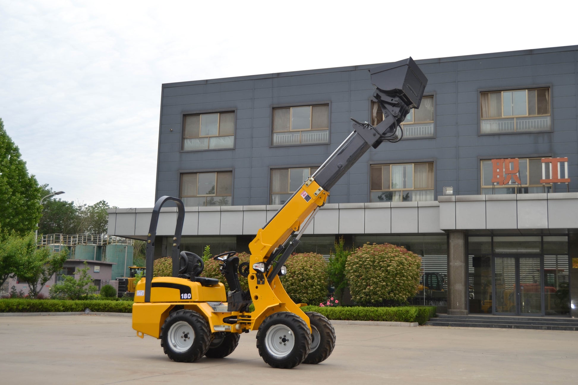 JT5WL800 compact wheel loader lifting bucket high with extended boom, showing stable articulated design for farm, landscaping and construction projects across Canada