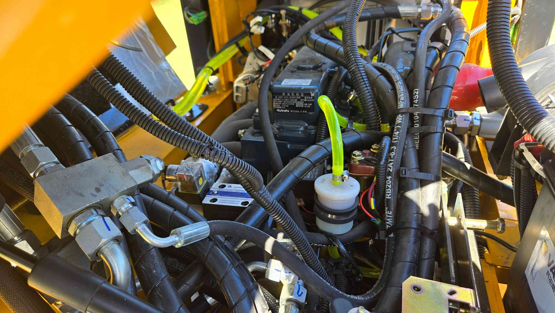 Hydraulic distribution block wiring harness fluid lines and control module inside the JT5WL800 compact wheel loader shown in a detailed close view for dependable farm landscaping and construction work across Canada