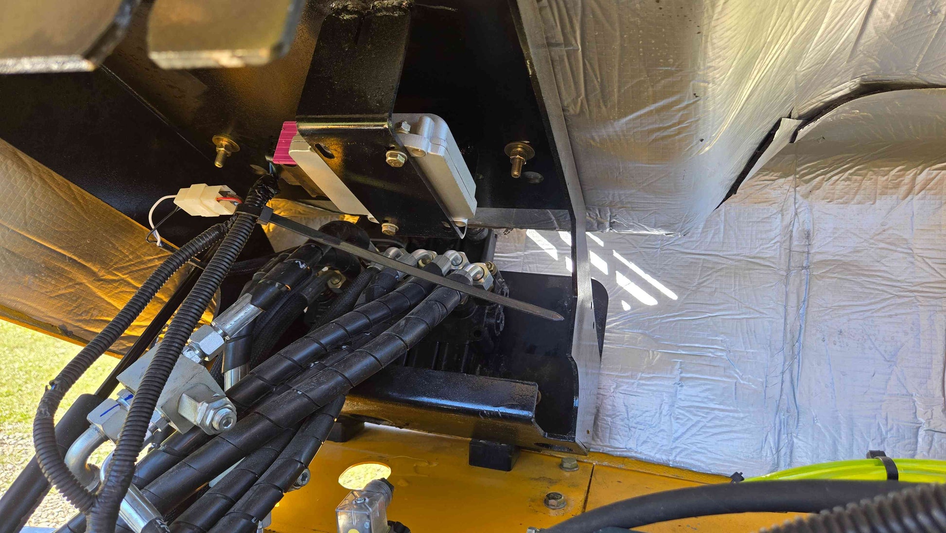 JJT5WL800 compact wheel loader hydraulic line mounting area showing hose routing and frame support for landscaping and construction work across Canada.