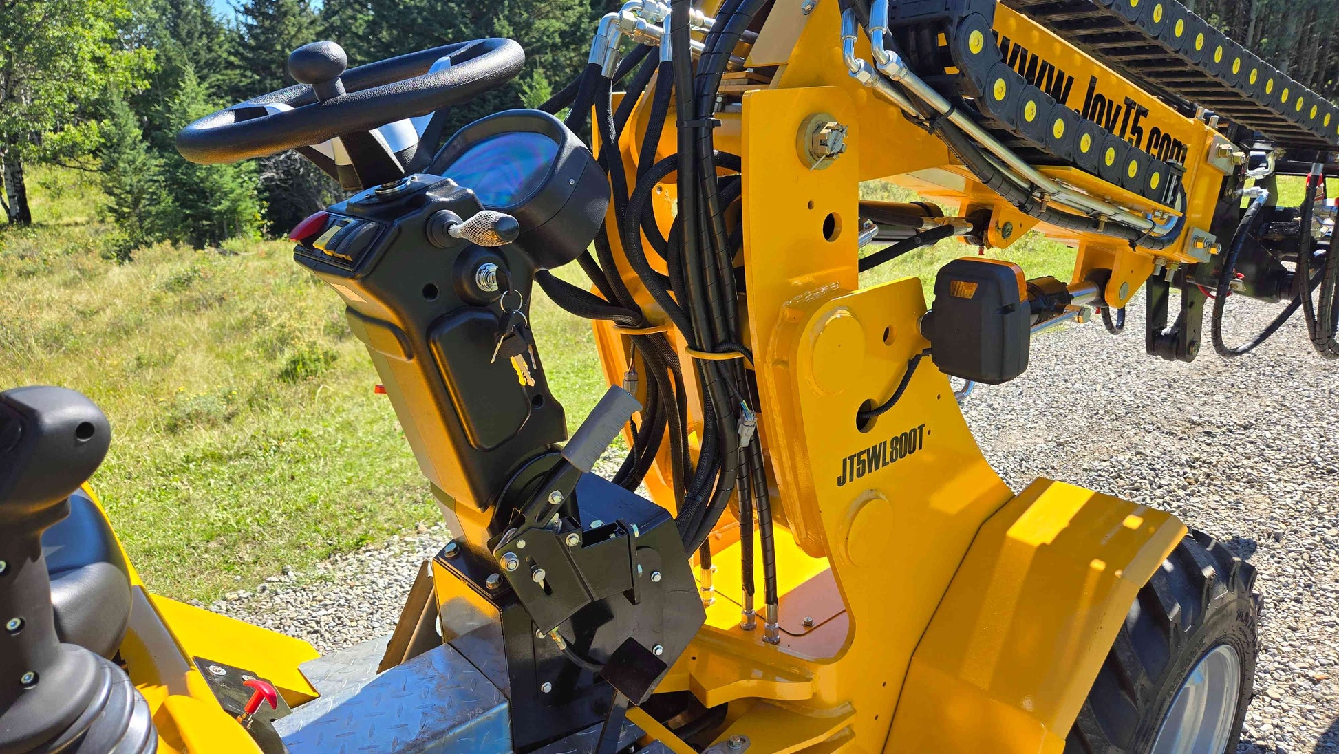 Steering column control panel and hydraulic line setup of the JT5WL800 compact wheel loader positioned beside the loader boom for smooth operation in farm landscaping and construction work in Canada