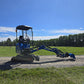 Side view of rippa r15 mini excavator for sale on gravel road with green field and blue sky background