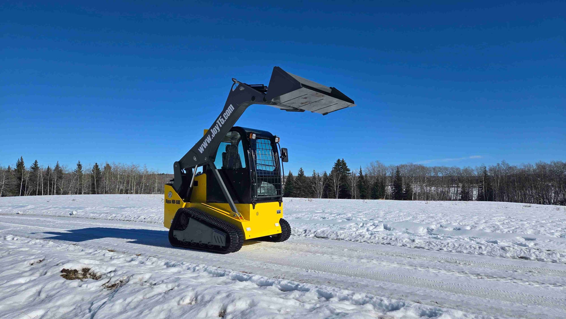 Angled side-front view of Rippa NDI680 compact skid steer loader with 74 HP engine and raised bucket in snowy field in Canada| JoyT5