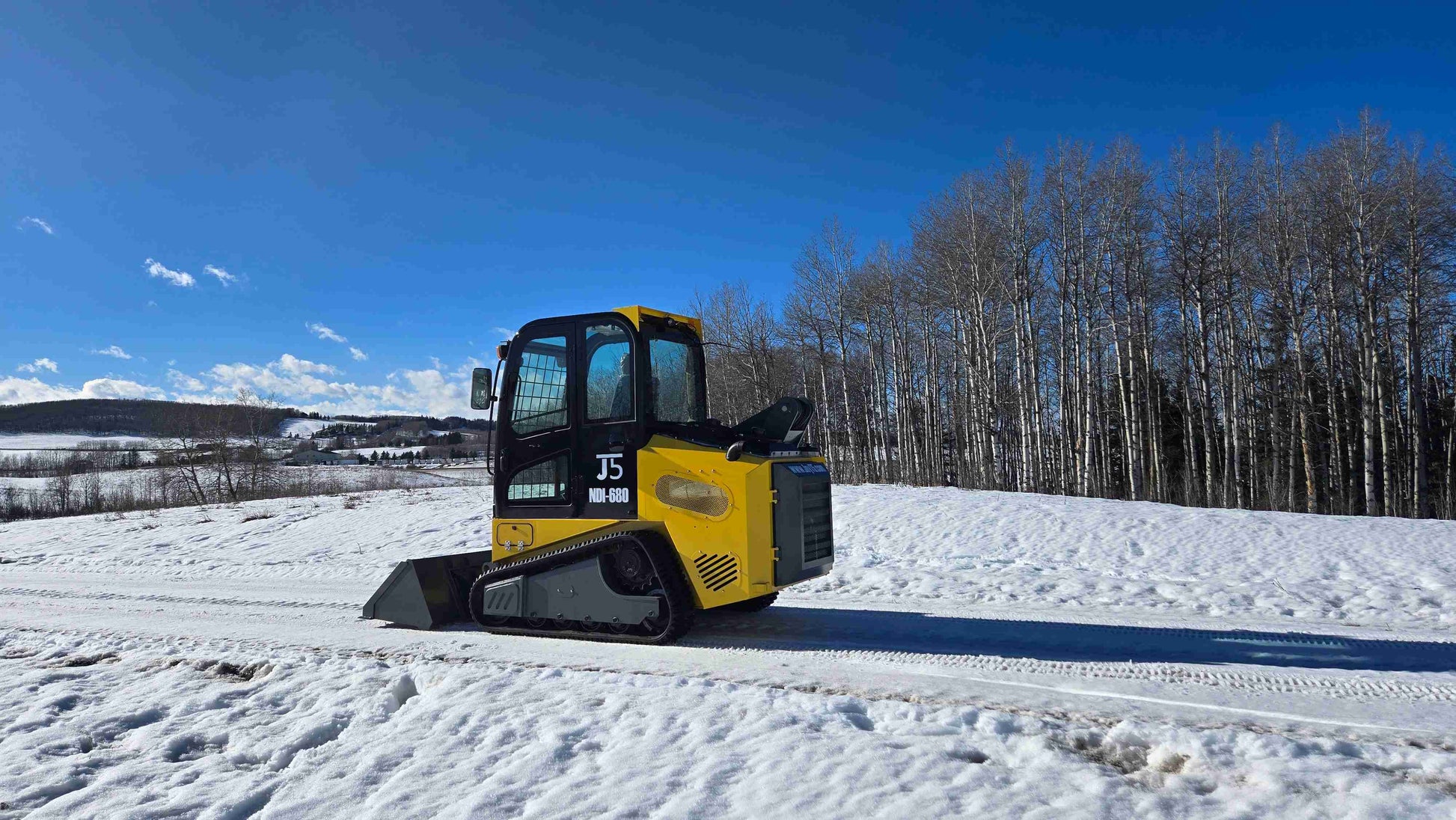 Rippa NDI680 heavy duty skid steer loader side profile with 74 HP engine and 1250kg lift on snowy ground in Alberta Canada | JoyT5