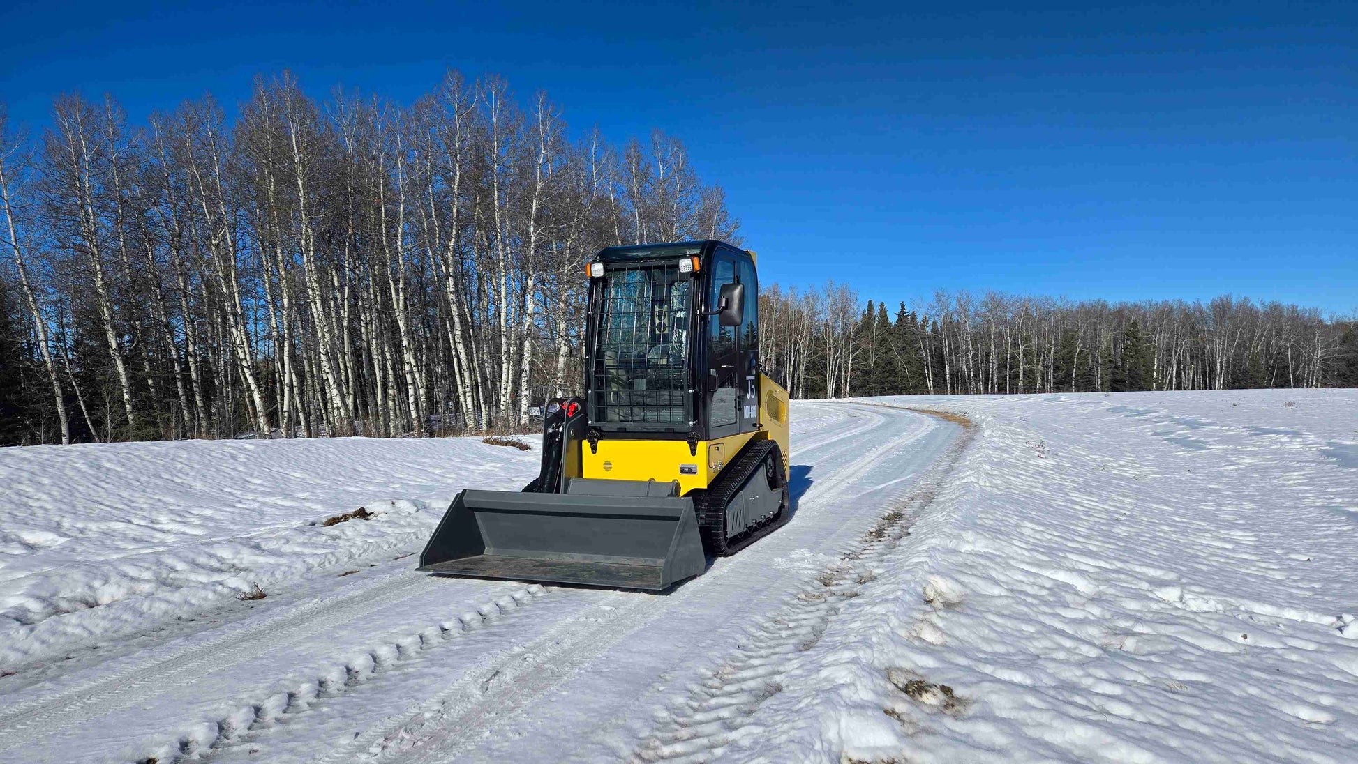 Rippa NDI680 skid steer 74 HP with front bucket operating on snowy road for construction landscaping and farming use in Canada by JoyT5