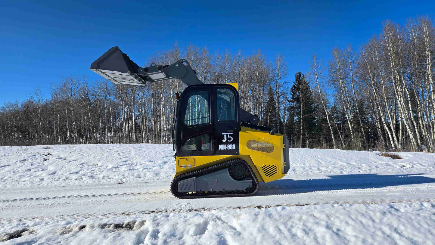 rippa NDI680 skid steer 74 HP compact tracked bucket loader lifting attachment on snowy ground in Canada for construction and landscaping

