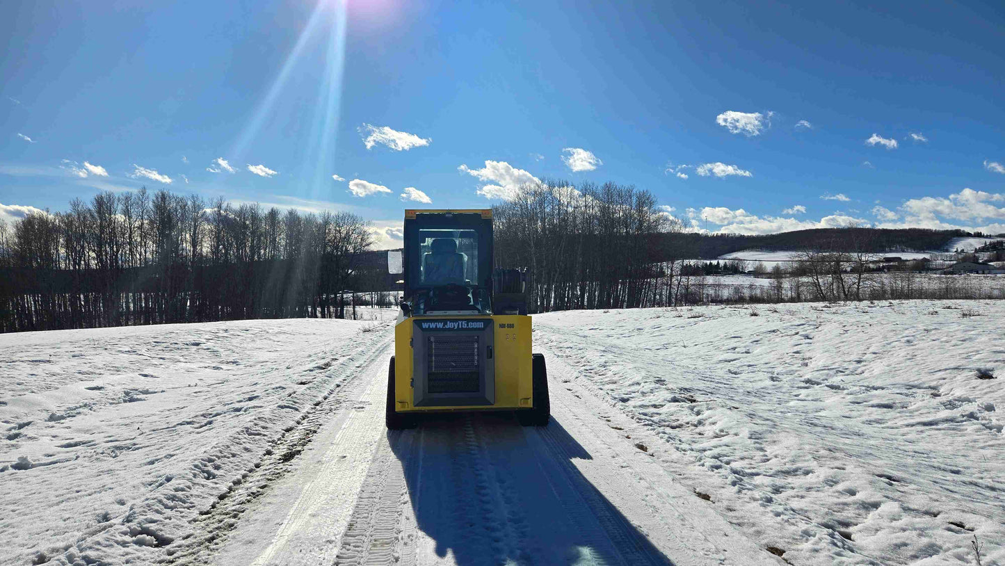 rippa NDI680 skid steer 74 HP compact tracked loader front view driving on snowy road in Canada for construction and snow clearing

