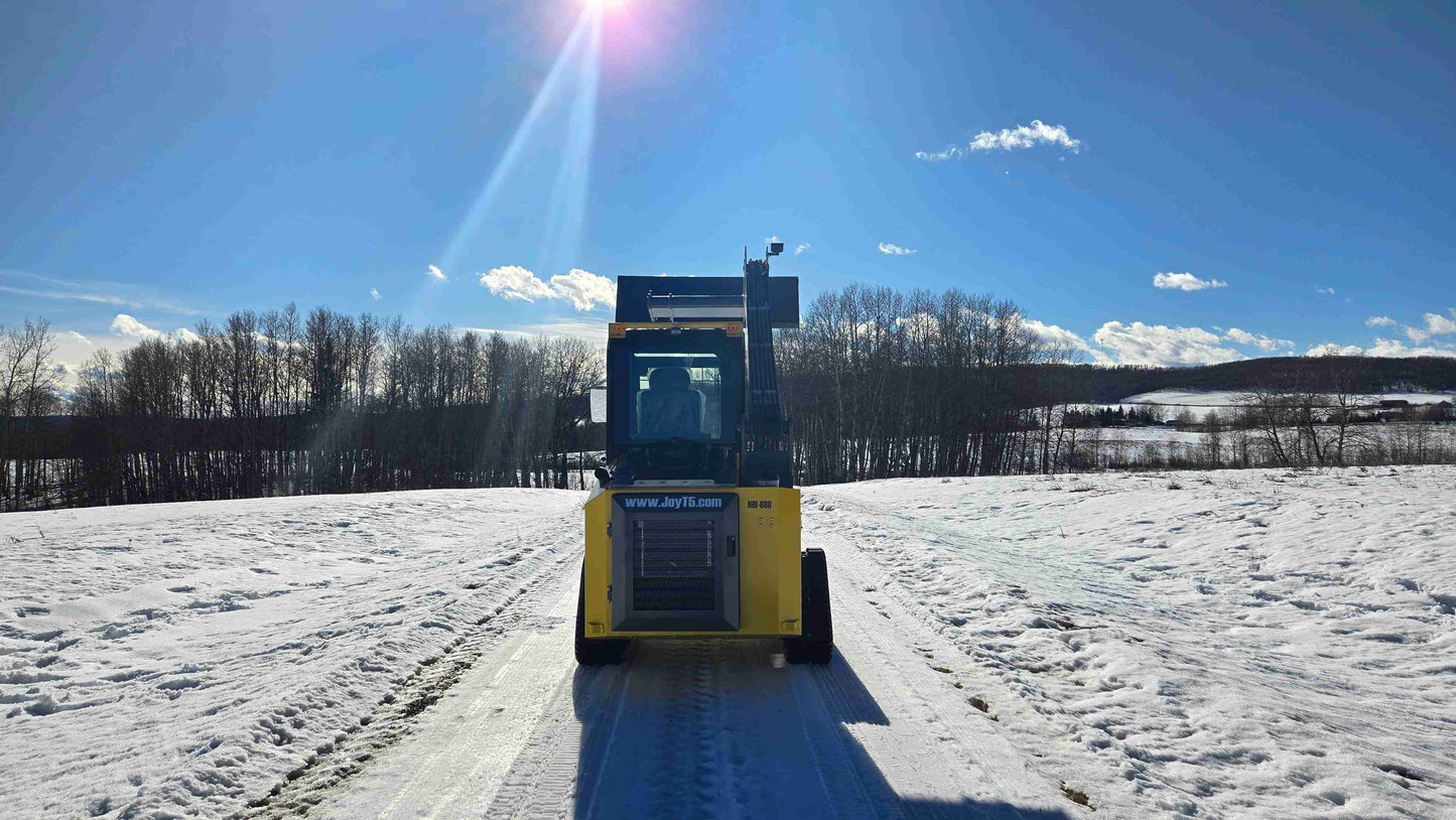 rippa NDI680 skid steer 74 HP compact tracked loader front view lifting bucket under sunlight on snowy ground in Canada for construction and landscaping work

