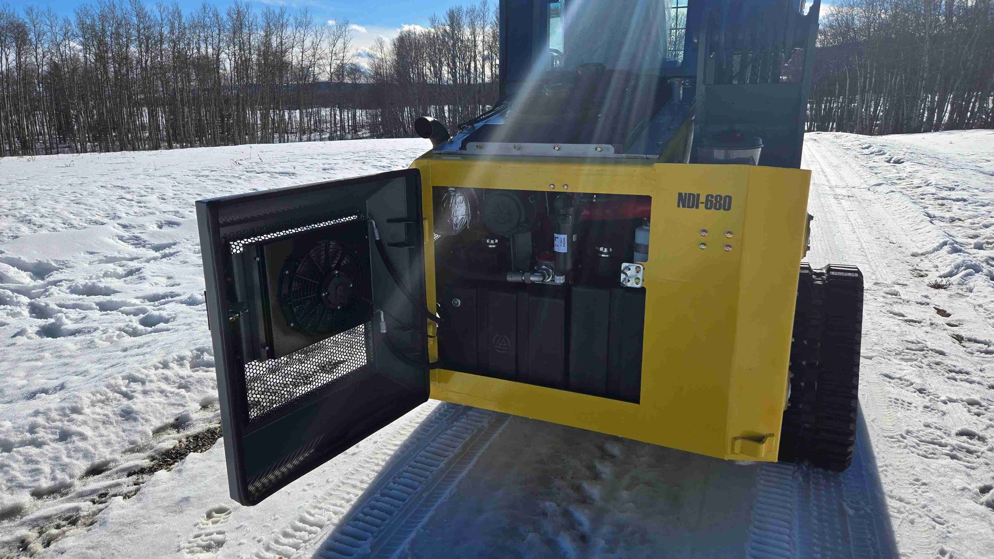 Rear view of Rippa NDI680 skid steer loader with engine service panel open showing cooling fan and hydraulic components for 74 HP Cummins machine used in construction and landscaping projects across Canada by JoyT5