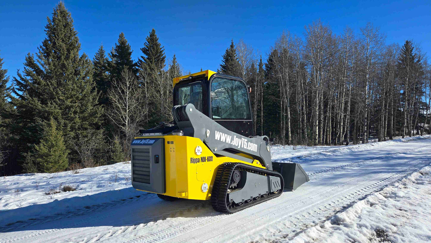 rippa NDI680 skid steer 74 HP tracked compact loader with bucket attachment operating on snowy road in Canada

