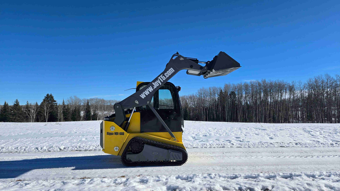 Left side view of Rippa NDI680 tracked skid steer with raised bucket on snowy road in Canada by JoyT5