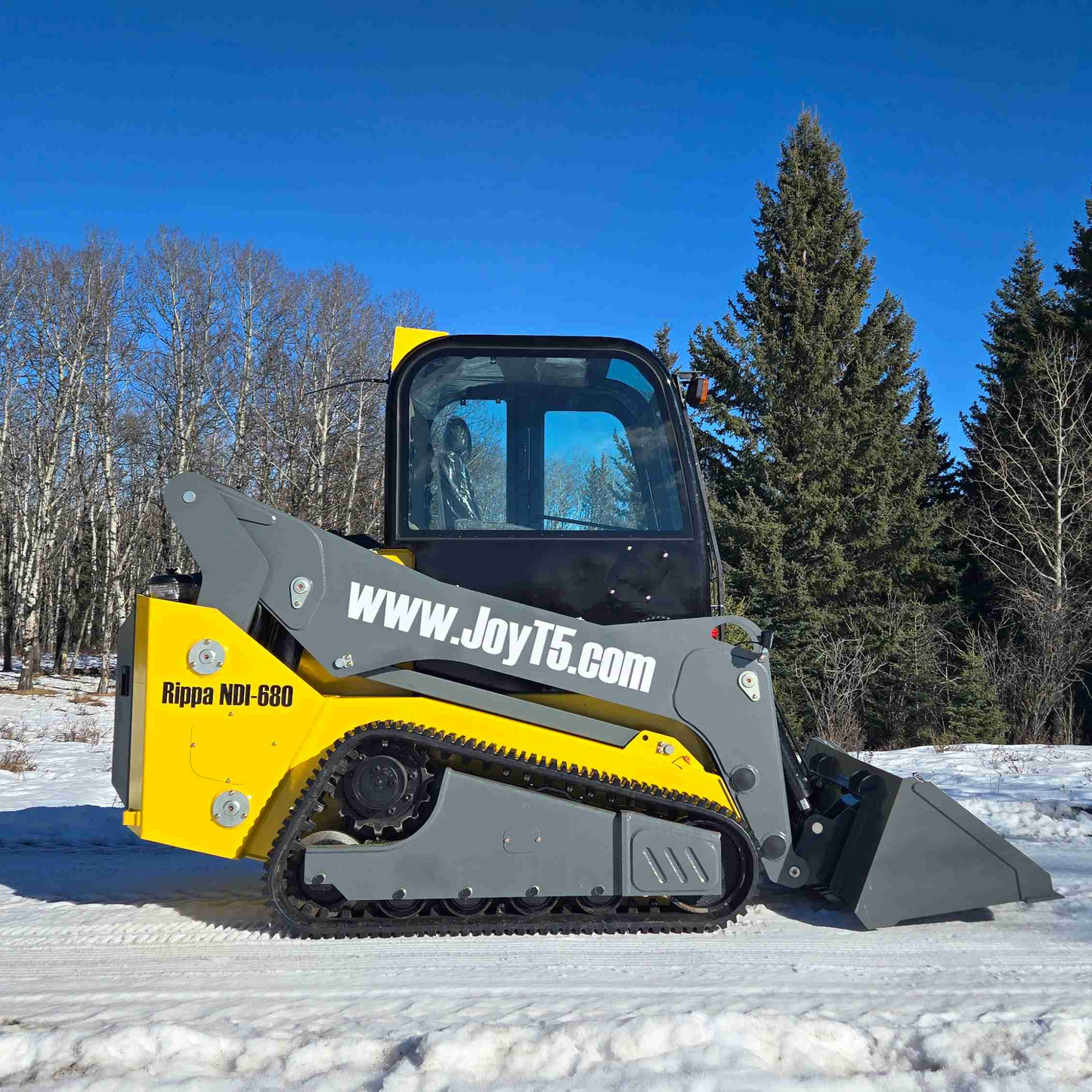 Side view of Rippa NDI680 tracked skid steer loader with bucket attachment working outdoors in snowy Canada by JoyT5