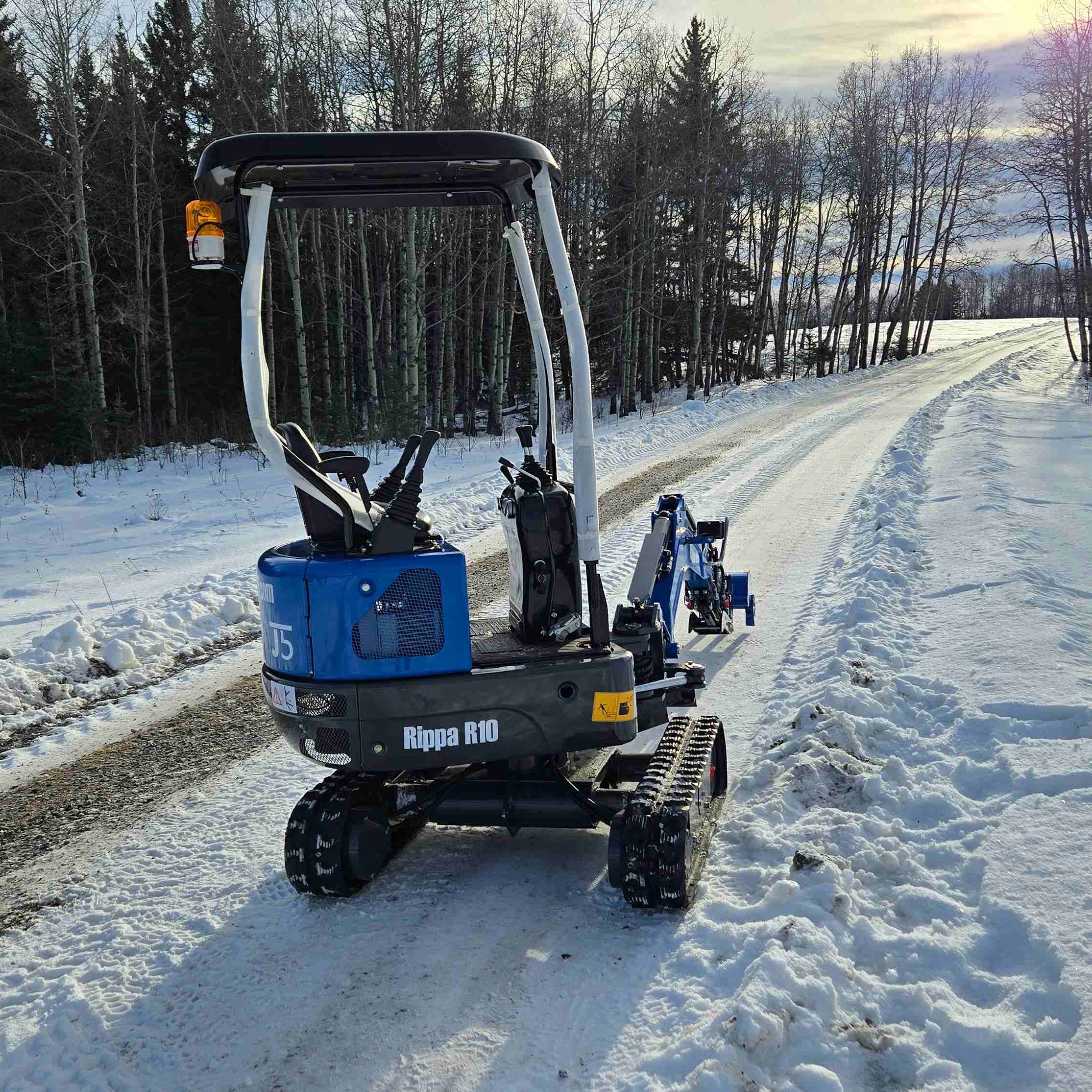 Rippa R10 mini excavator on a snowy countryside road in Canada from rear view with JoyT5 dealer machine ready for small excavator projects landscaping and compact construction equipment