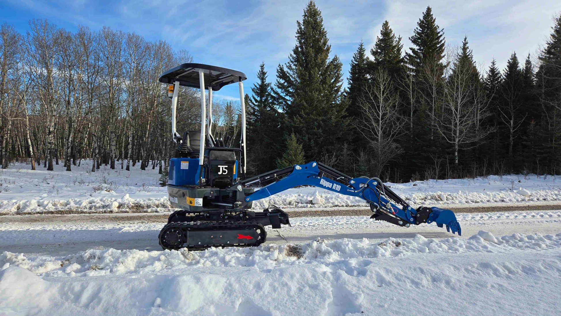 Rippa R10 mini excavator working in the snow on a rural road in Canada with the arm extended showing compact digging capability from JoyT5 for landscaping and small construction projects