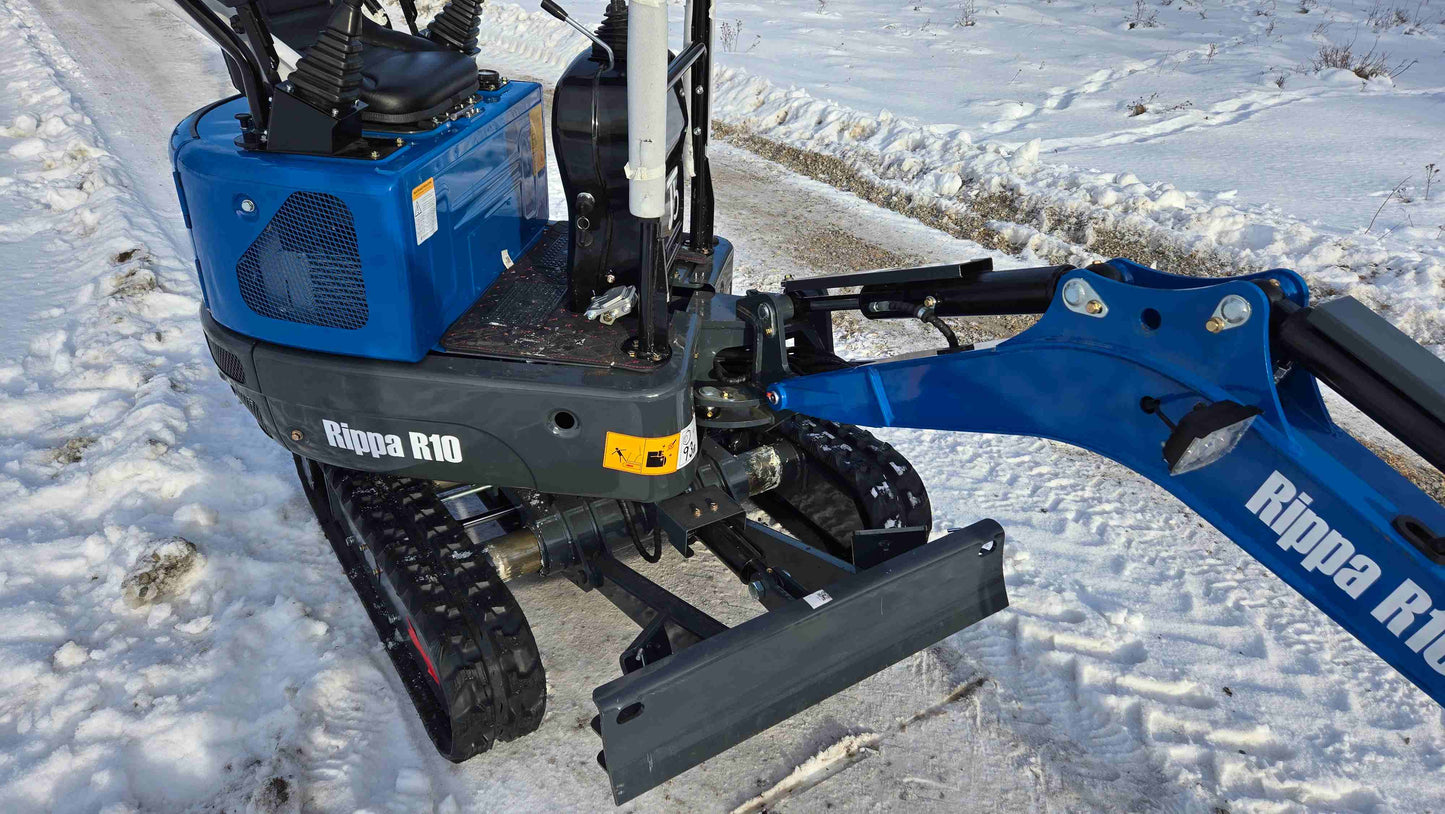 Close-up of Rippa R10 mini excavator hydraulic arm and front blade on snowy ground in Canada, compact and durable digger by JoyT5 for construction work.