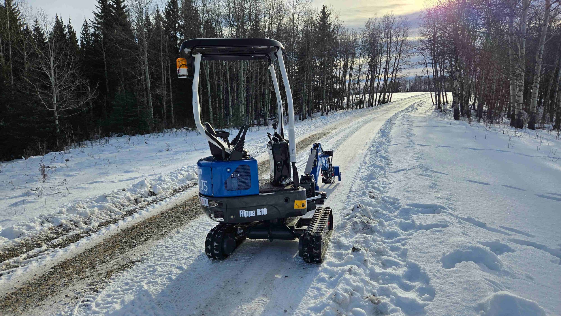 Rippa R10 mini excavator on snowy winter road in Canada, compact construction digger by JoyT5 showcasing durability and performance in cold conditions.