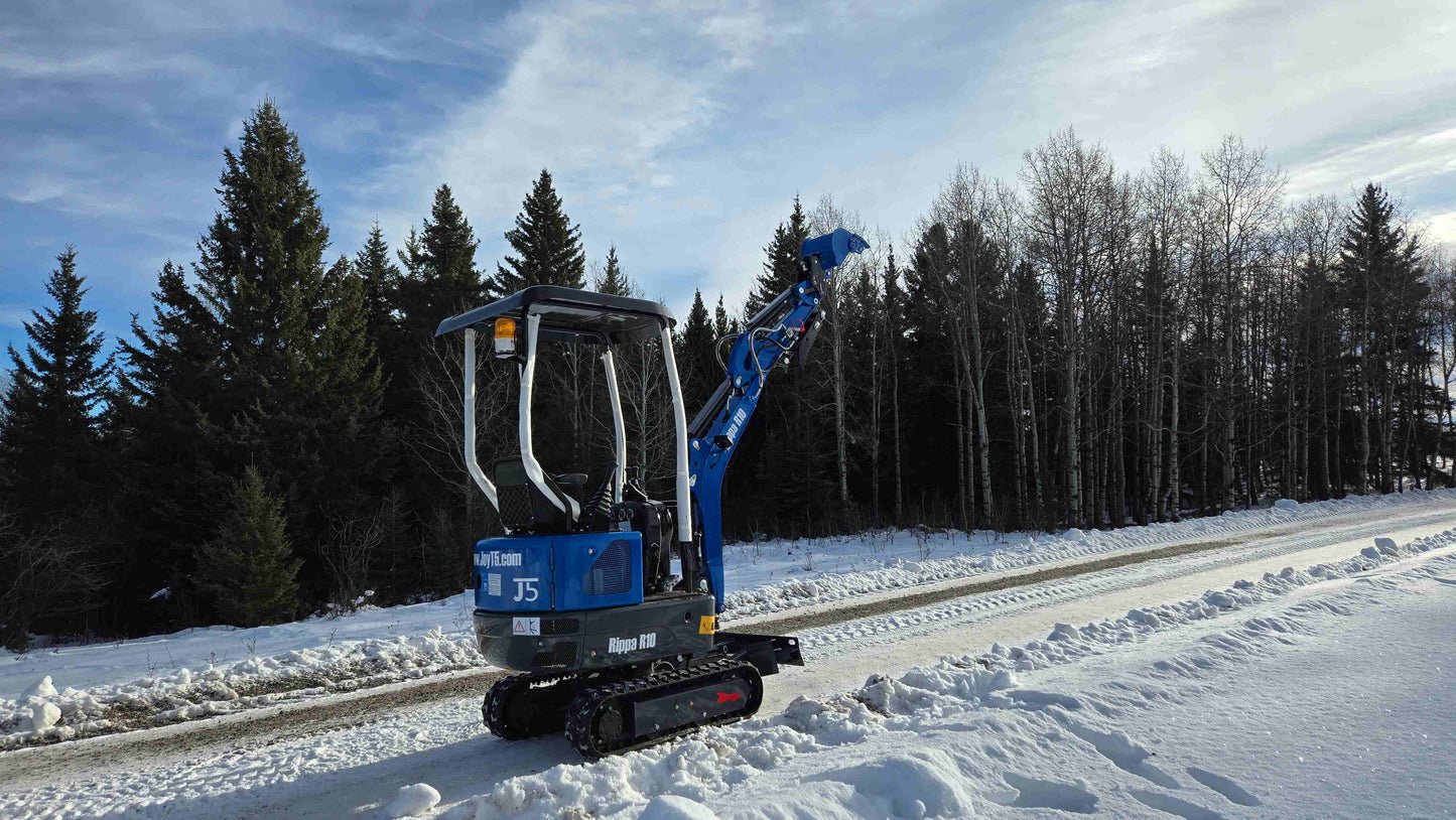 Rippa R10 Mini Excavator on snowy road with raised boom and forest background