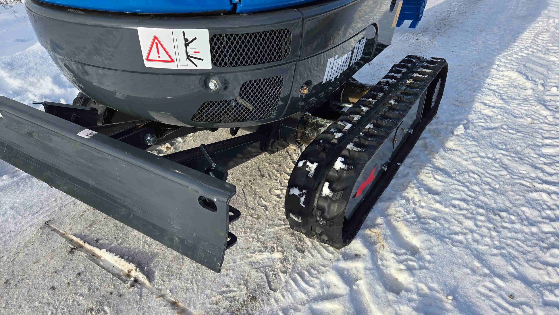 Close-up view of Rippa R10 Mini Excavator track and front blade on snow