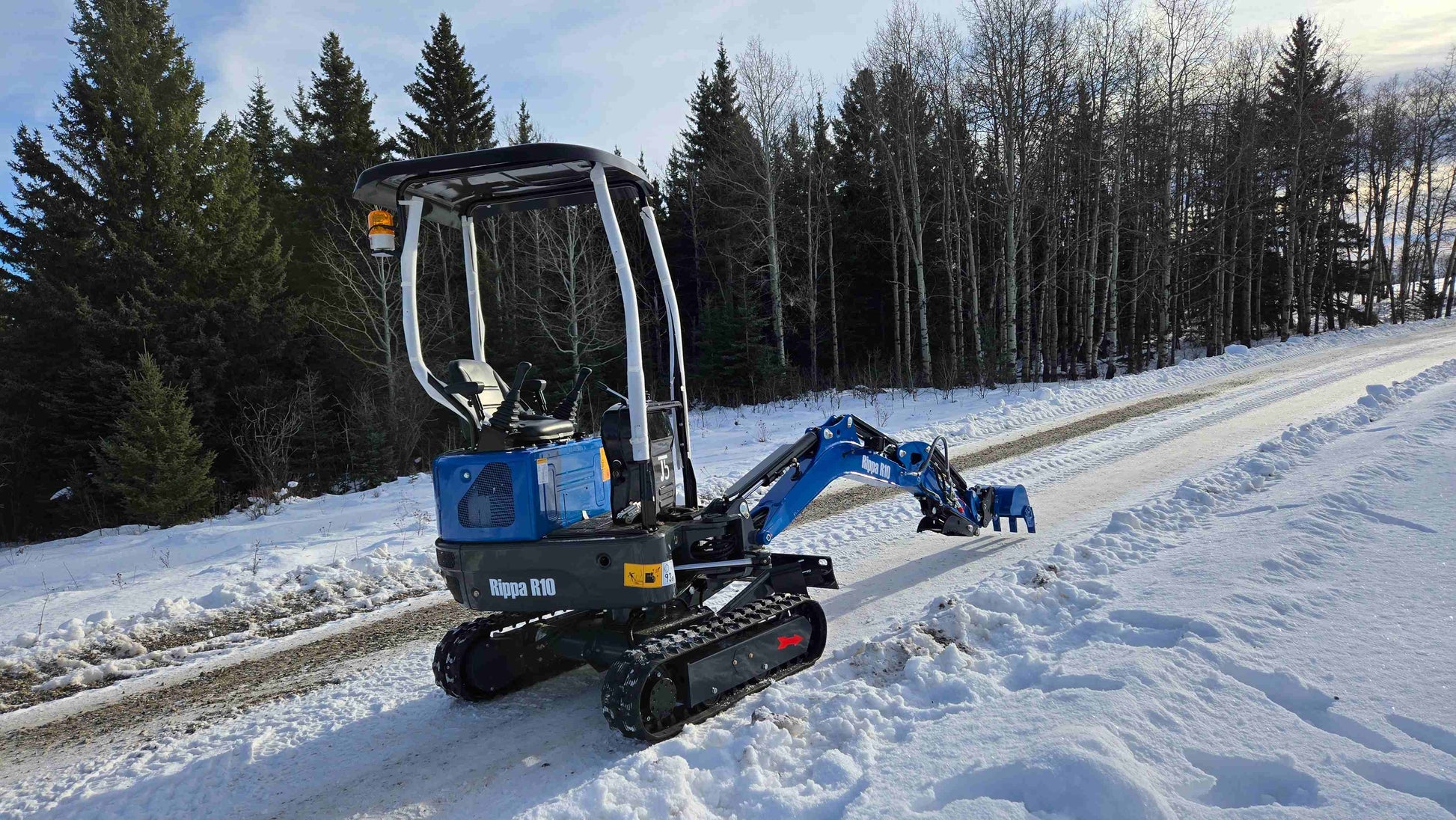 Rippa R10 mini excavator operating on snowy road in Canada, compact and powerful digger by JoyT5 for small construction and landscaping projects.