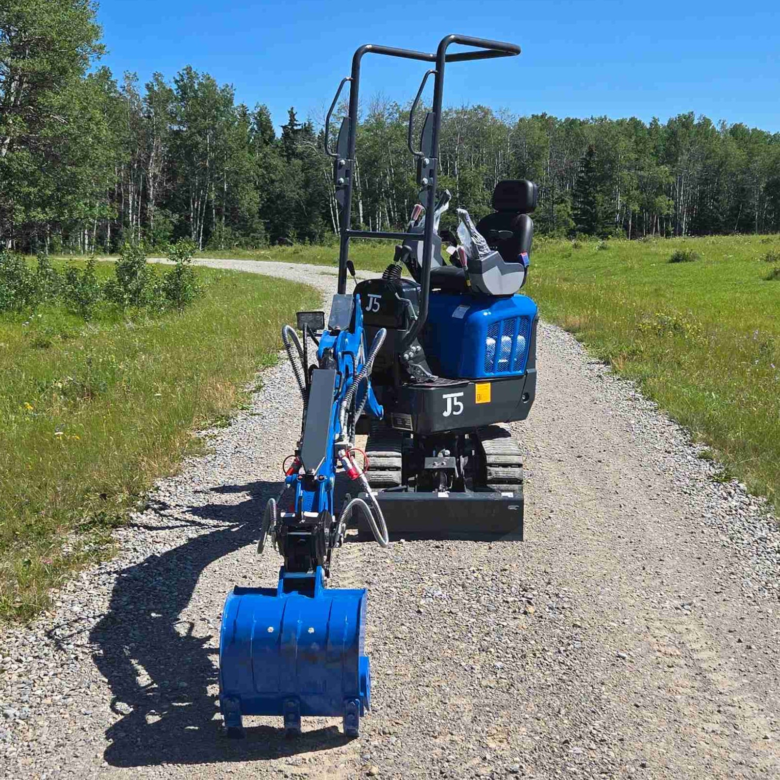 Rear view of Rippa R13 1.3 ton mini excavator with bucket on gravel road | Compact mini excavator for construction and landscaping jobs in Canada with JoyT5 support