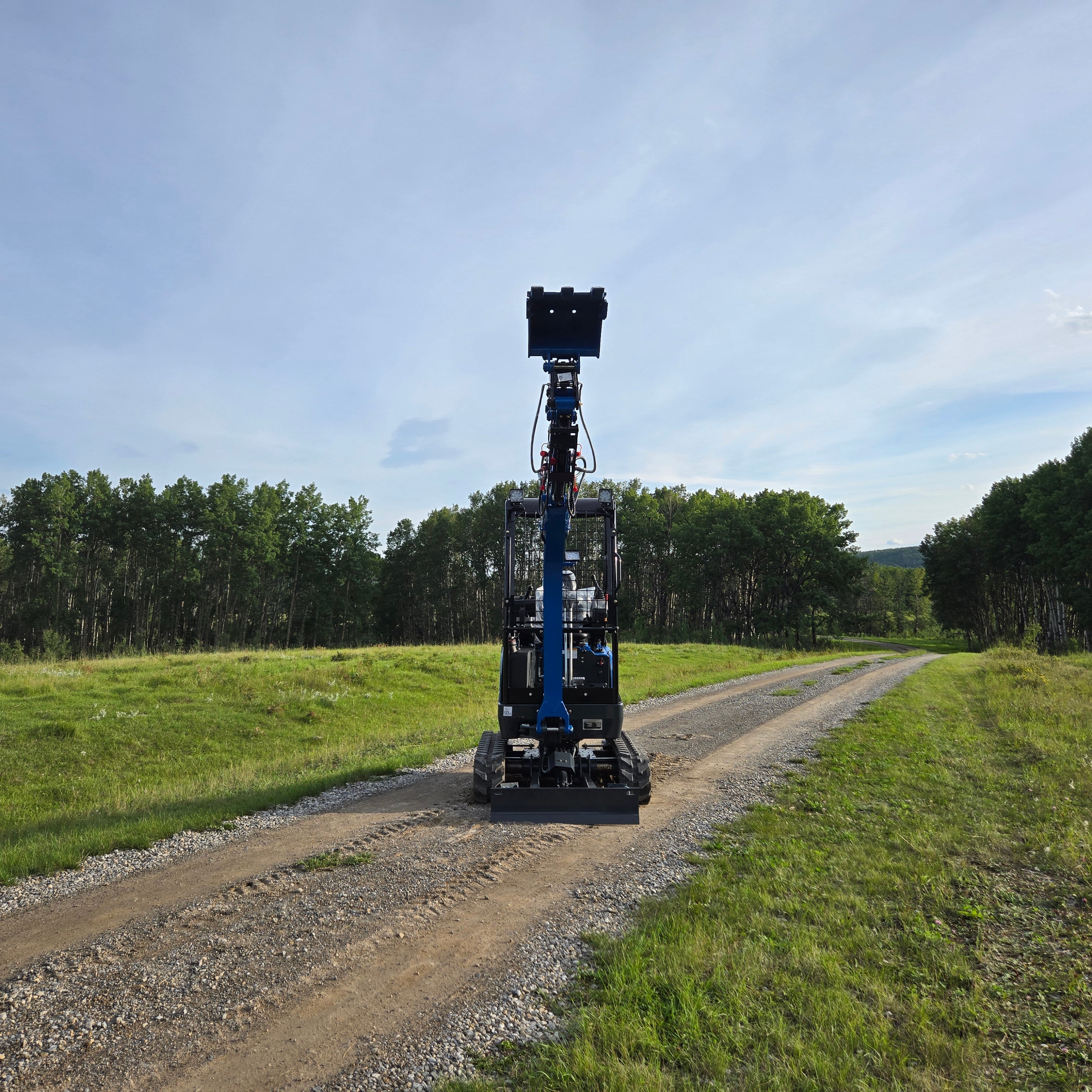 Front view of Rippa R18- Mini Excavator with raised boom and bucket on a gravel road.