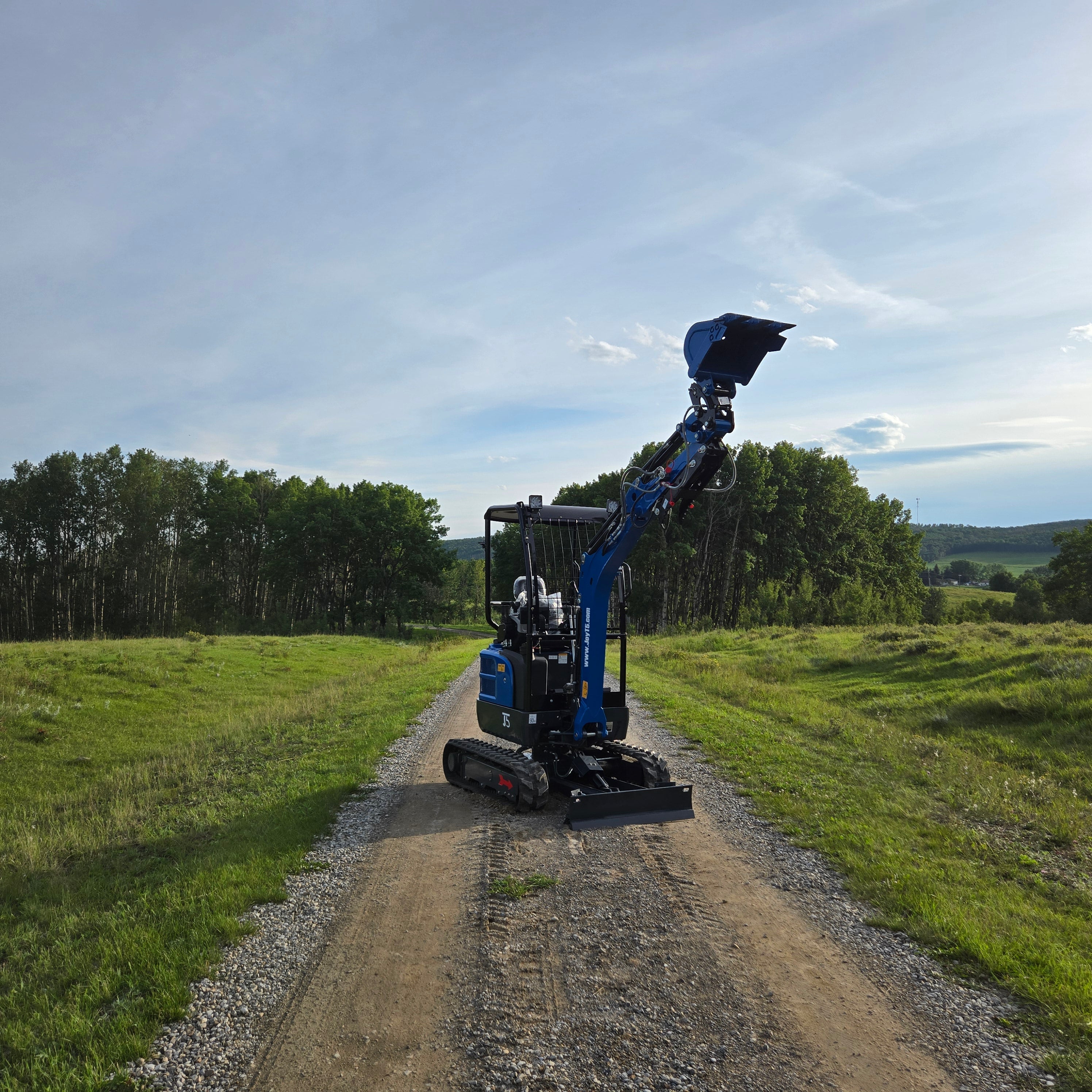 Rippa R18- Mini Excavator on gravel road with raised arm and bucket in countryside.
