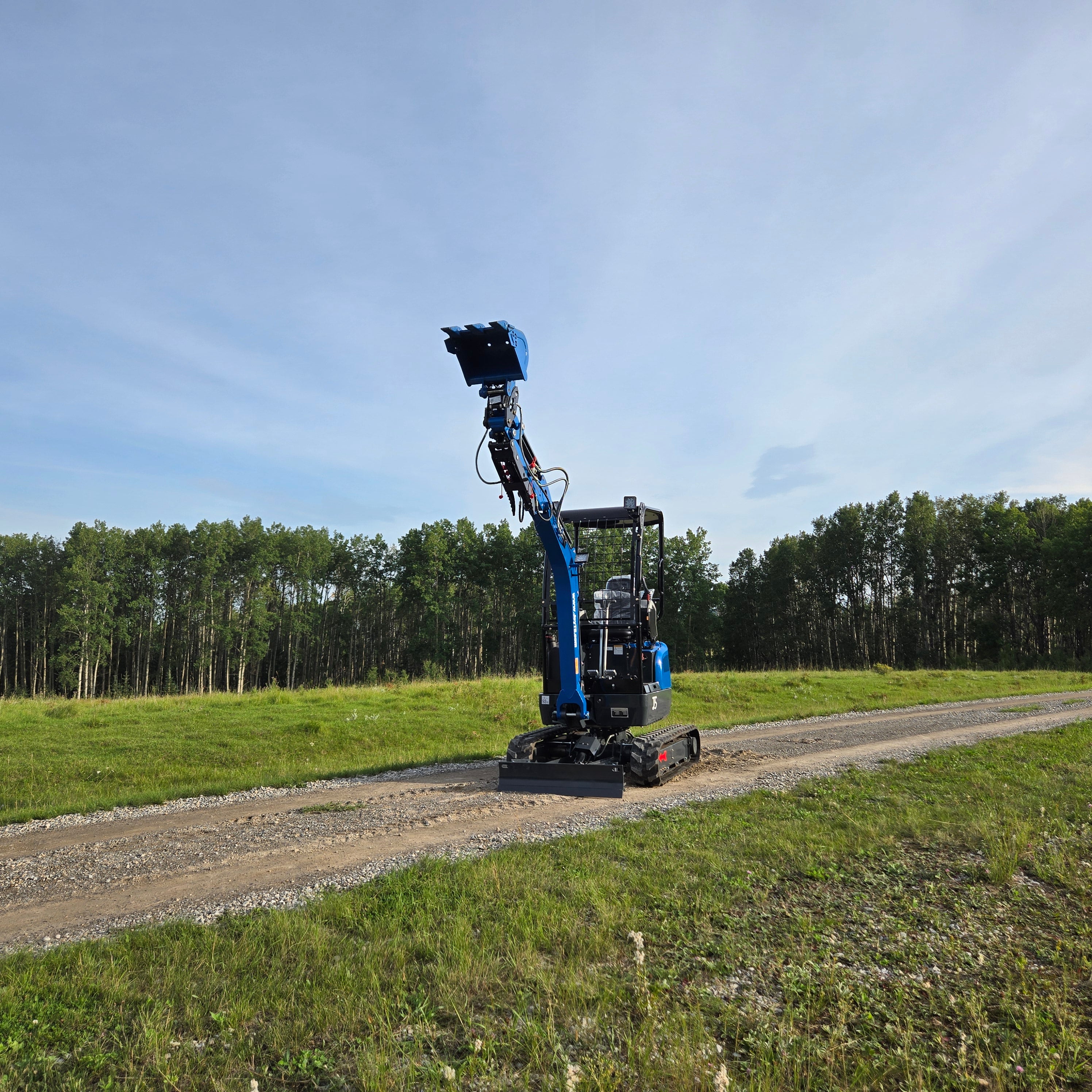 Rippa R18- Mini Excavator operating on a gravel road with a raised boom and bucket.