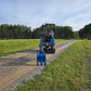 Rear view of JoyT5 Rippa R18 Mini Excavator with blue digging bucket on a gravel road surrounded by greenery