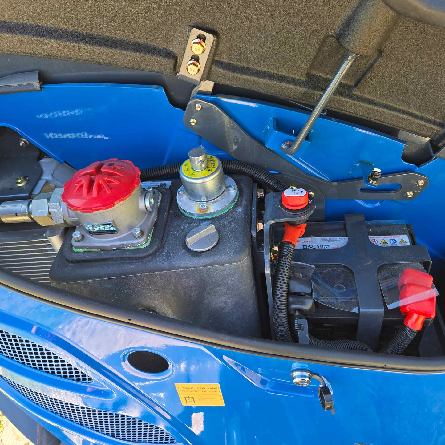 Engine and battery compartment of Rippa R22 mini excavator – compact 2 ton excavator for sale in Canada with Yanmar engine, showing hydraulic filter and electrical components for maintenance.

