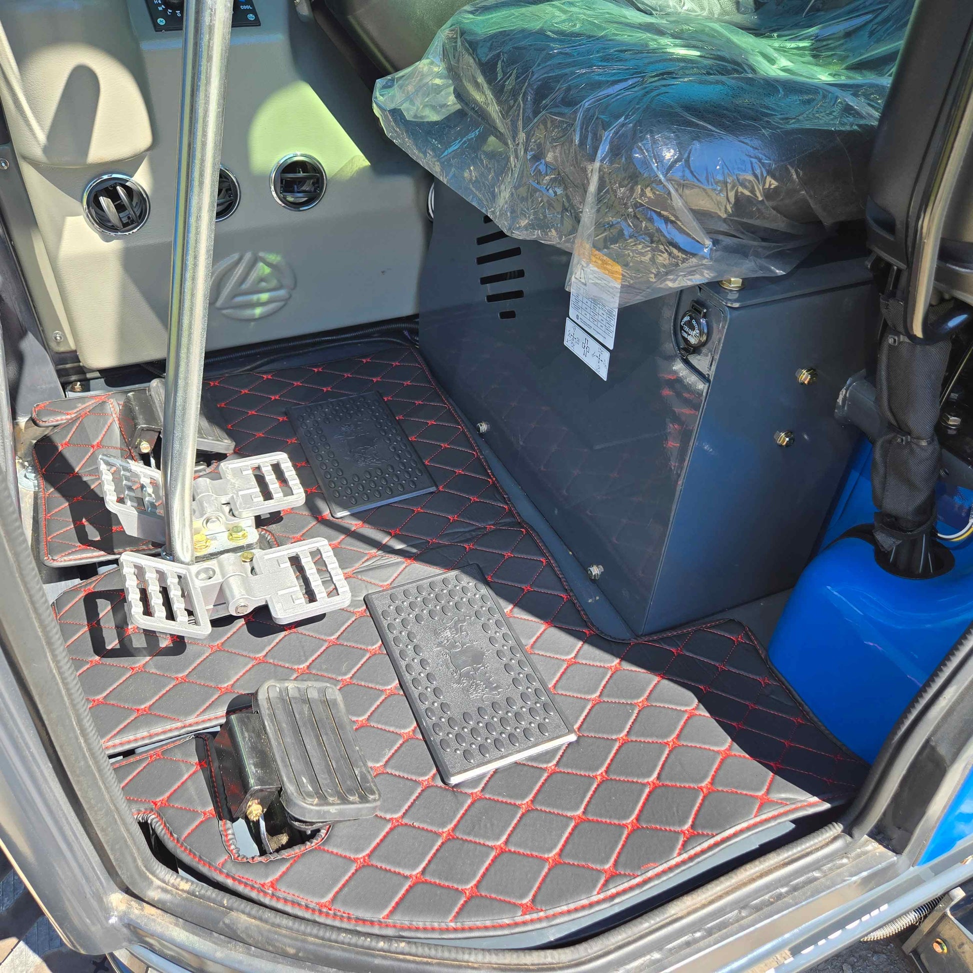 Close-up view of the Rippa R22 Mini Excavator for sale cabin floor showing pedals, control levers, and seat wrapped in protective plastic.
