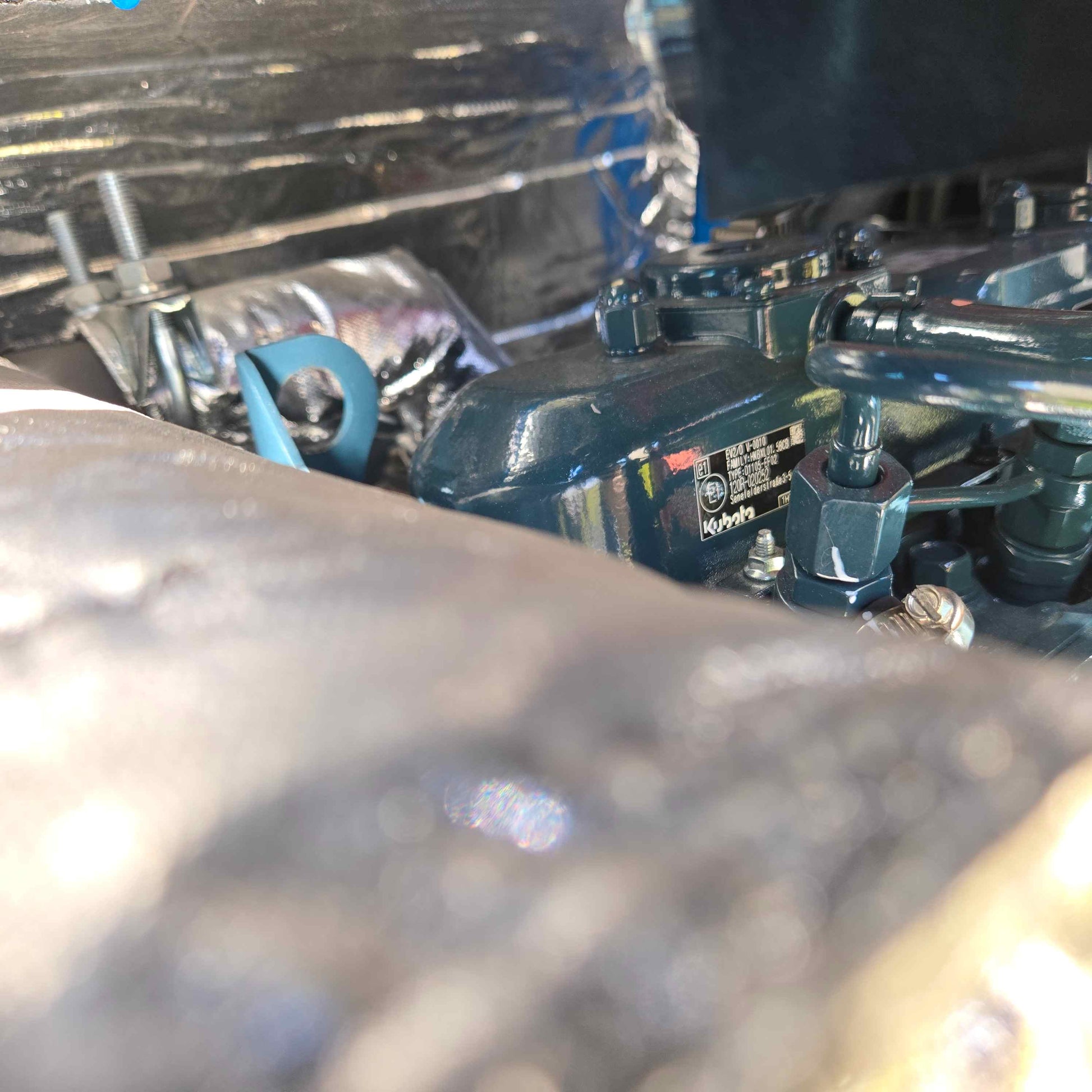 Close-up view of the Rippa R22 mini excavator for sale engine showing the metal serial plate with technical details in Chinese, partially covered by surrounding engine parts.
