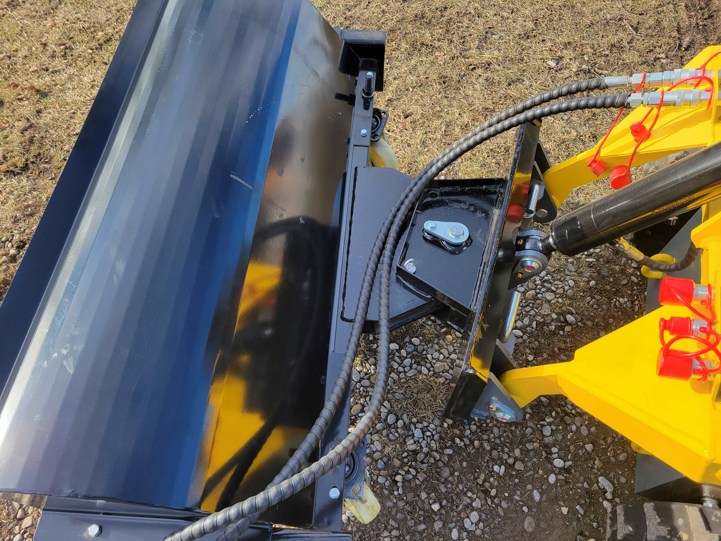 Tracked mini skid steer 23 HP loader sweeper attachment close up showing hydraulic hose connection in Canada

