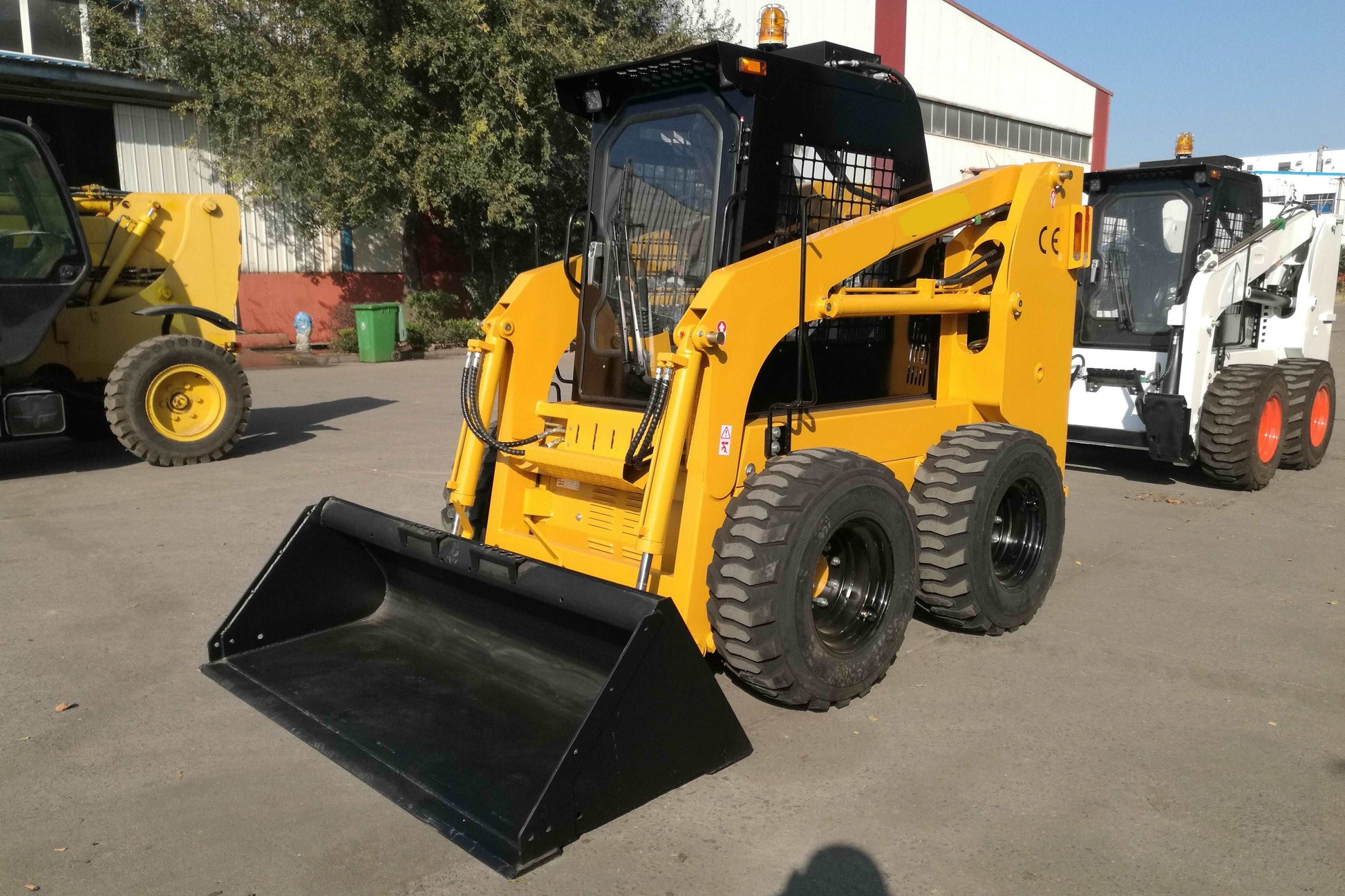 Yellow wheeled skid steer loader parked outdoors in Canada showing compact design and front bucket for construction and farming use

