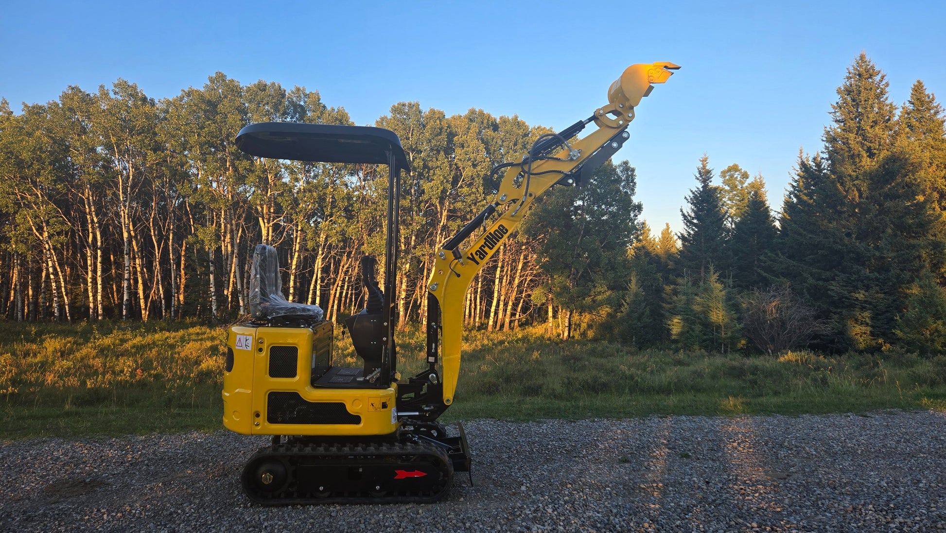 Side view of YardHoe YH12 / Rippa R319 mini excavator with raised boom and bucket, compact digger for landscaping and construction work.
