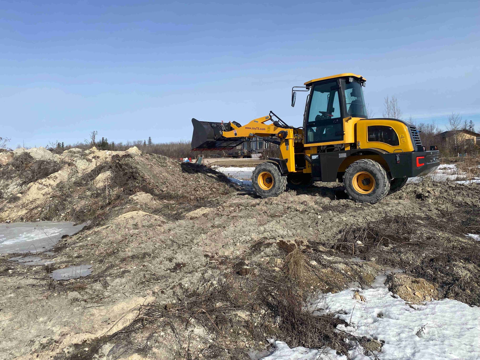 Yellow wheel loader moving soil and sand on construction site during land preparation work