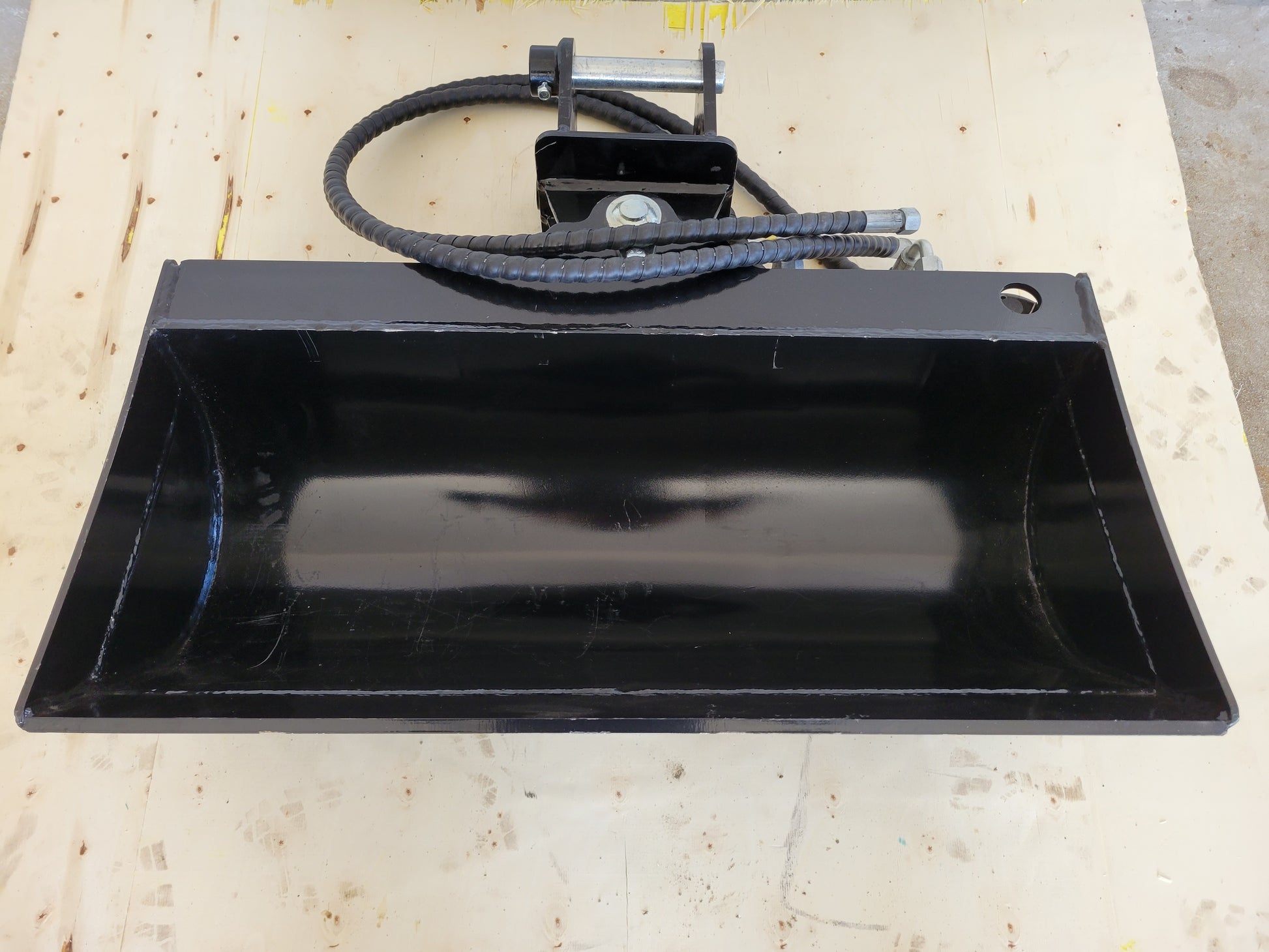 Hydraulic tilt bucket front view showing wide heavy duty design with hydraulic hoses for excavator digging and grading work in Canada

