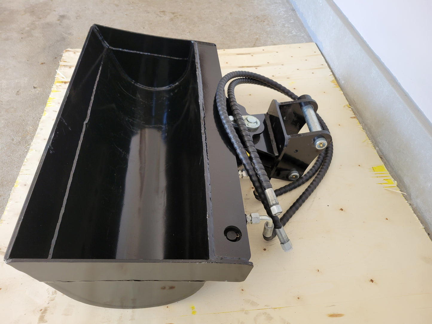 Hydraulic tilt bucket side view showing hydraulic hoses and wide curved bucket design for excavator grading and digging work in Canada

