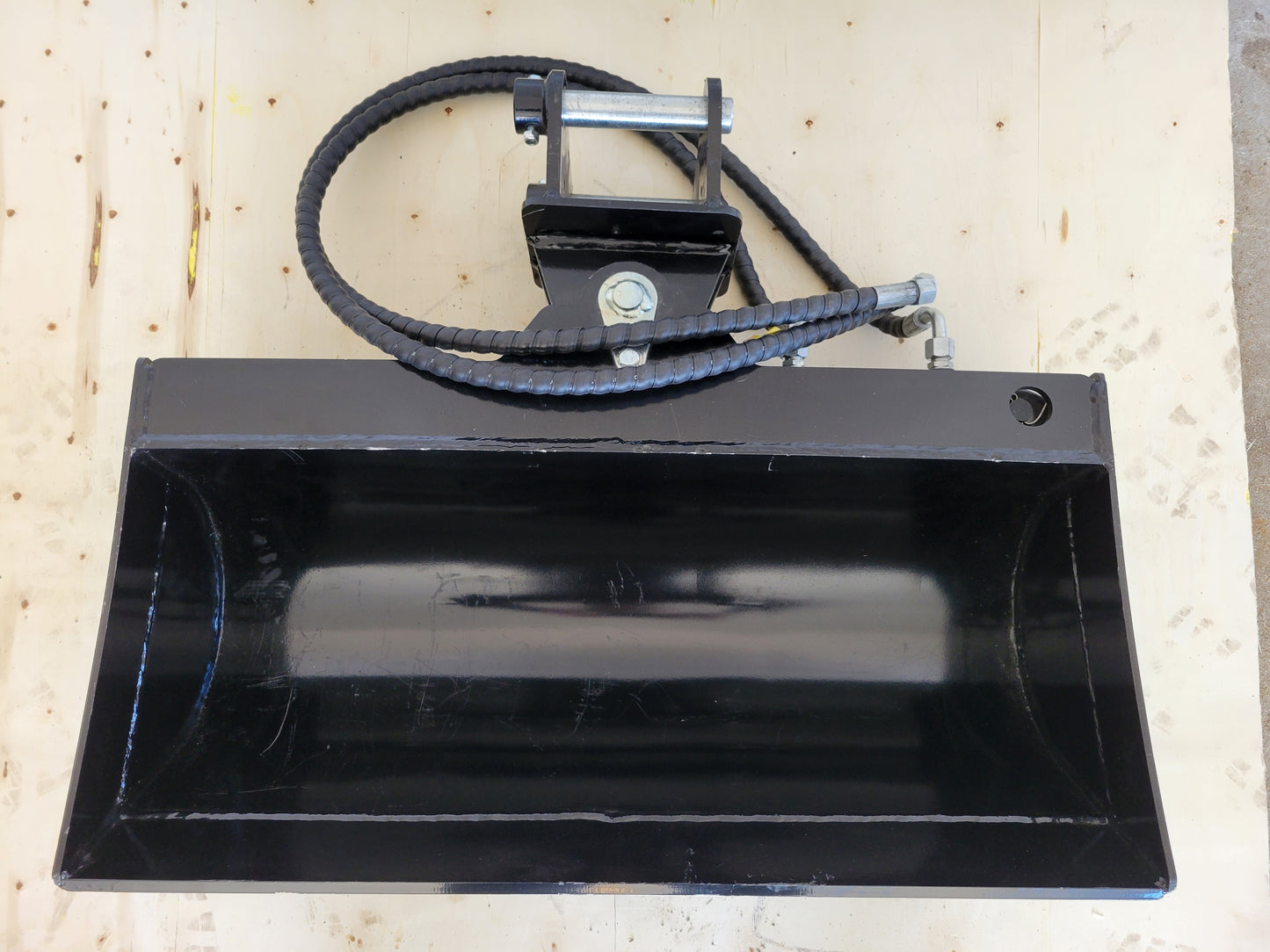 Hydraulic tilt bucket top view showing wide curved design and hose attachment for excavator grading digging and construction projects in Canada

