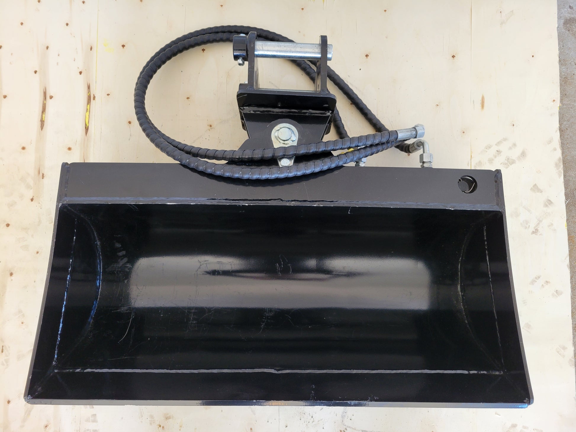 Hydraulic tilt bucket top view showing wide curved design and hose attachment for excavator grading digging and construction projects in Canada

