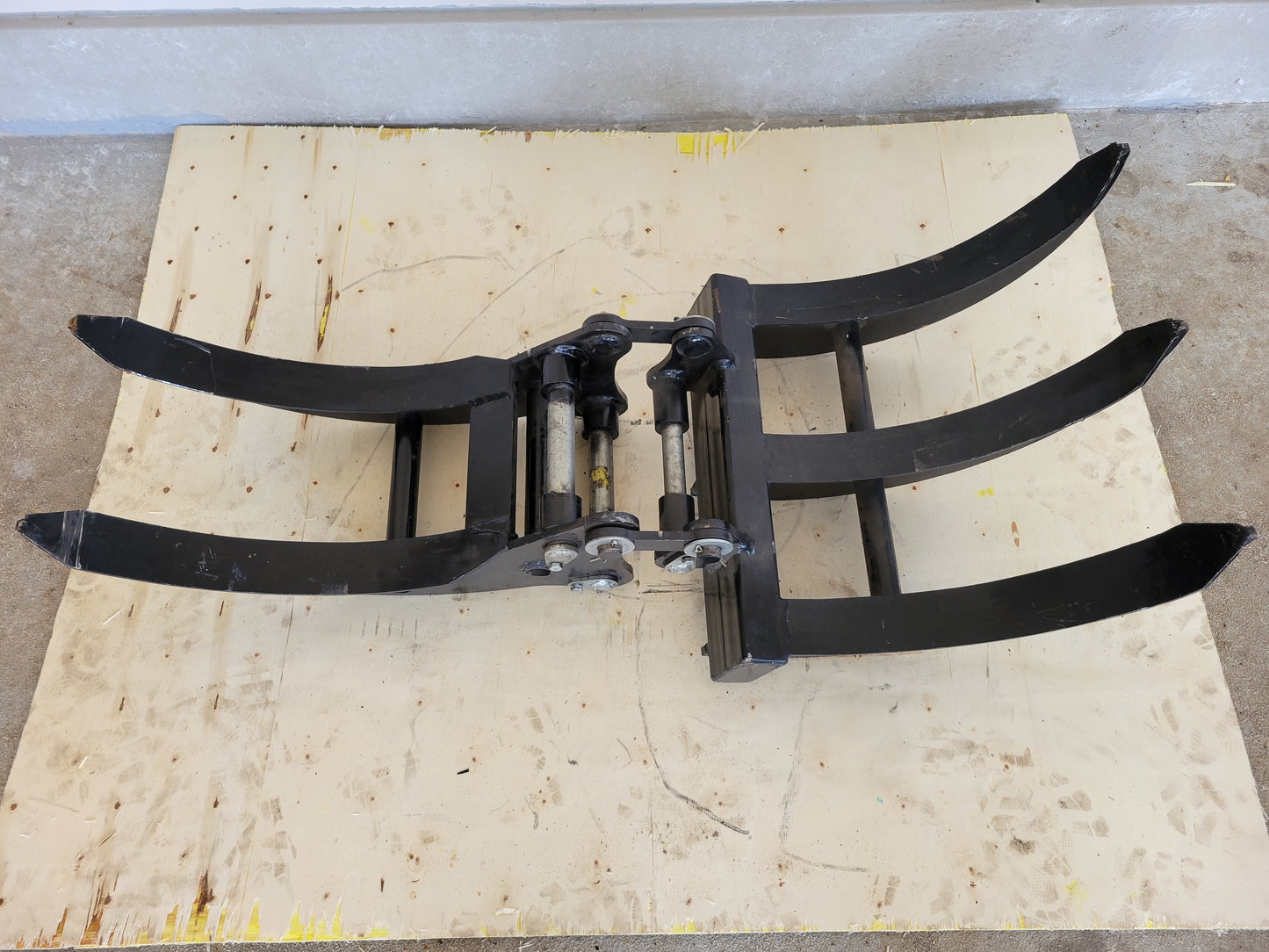 Mini excavator grapple attachment top view showing curved heavy steel arms for demolition and landscaping work in Canada